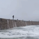 Big wave washes fisherman into the ocean