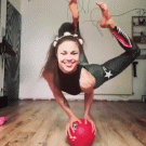 Girl balancing on a ball puts sunglasses on