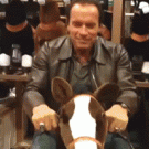 Arnold Schwarzenegger riding a toy horse