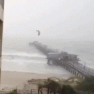 Kite surfer flies over pier
