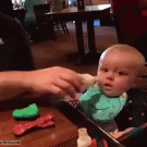 Dad squirts milk into baby's mouth